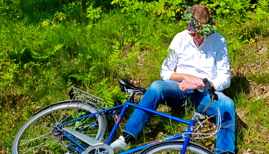 En man sitter i gräs och har trillat med sin cykel.