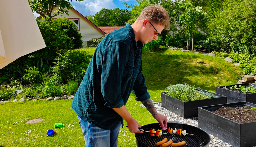 En man står och grillar.