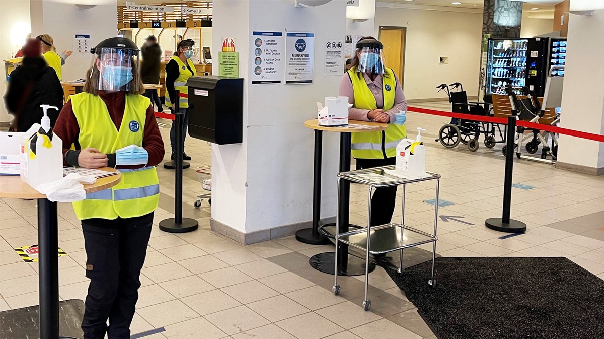Två medarbetare i entrén på Uddevalla sjukhus med visir och munskydd