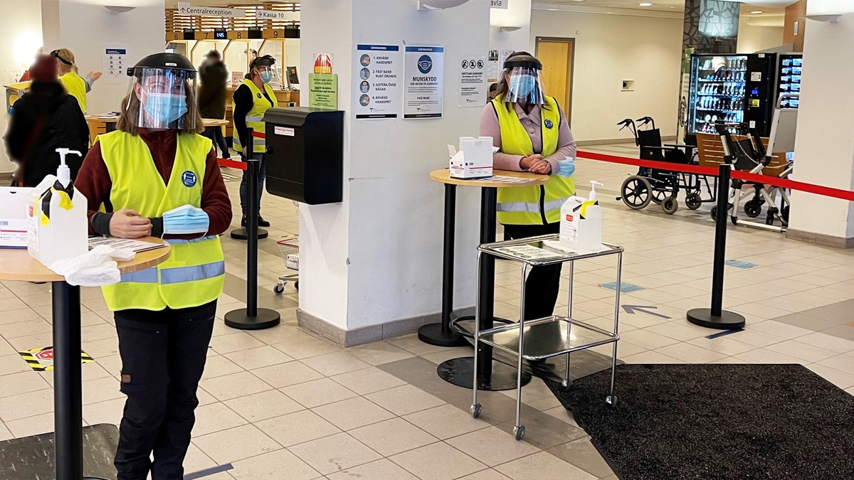Två medarbetare i entrén på Uddevalla sjukhus med visir och munskydd