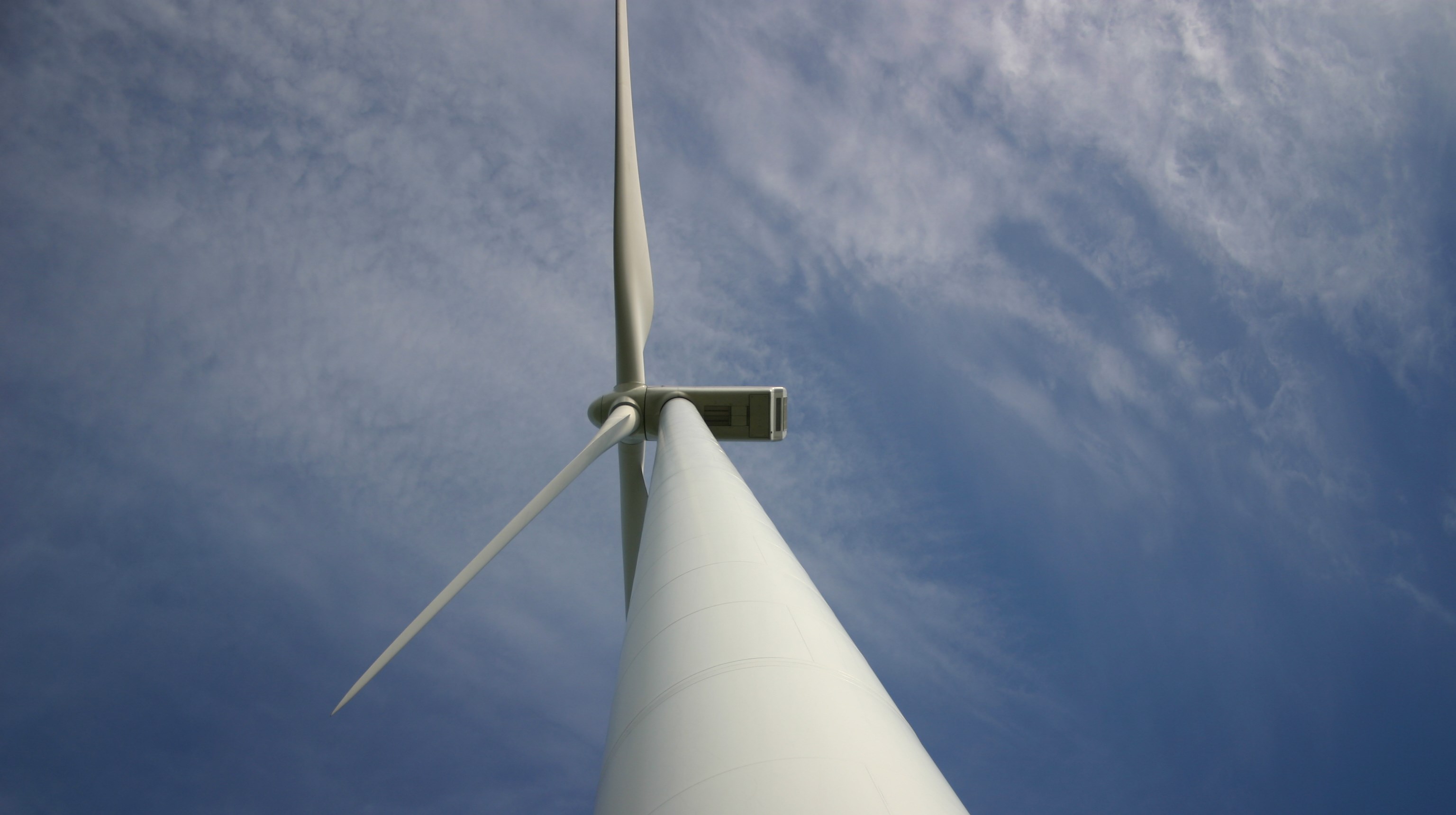 Bild på ett vindkraftverk taget nedifrån.